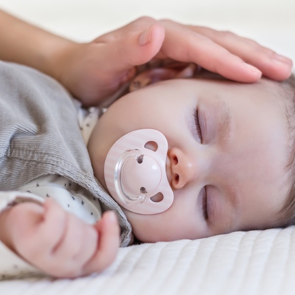 sleeping baby being coached with hand on head